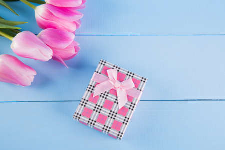 Bouquet of tender pink tulips with pink gift box on light blue wooden backgroundの写真素材