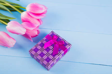 Bouquet of tender pink tulips with purple gift box on light blue wooden backgroundの写真素材