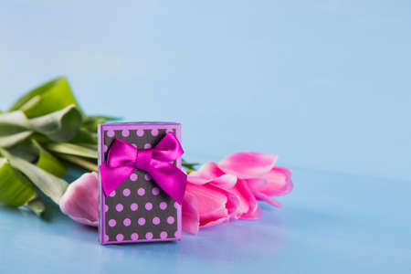 Bouquet of tender pink tulips with purple gift box on light blue wooden backgroundの写真素材