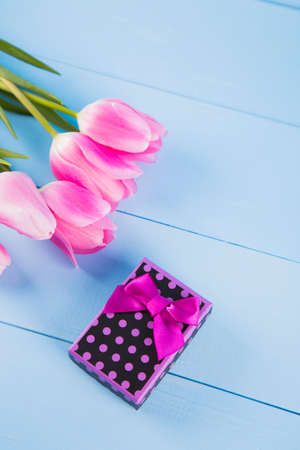 Bouquet of tender pink tulips with purple gift box on light blue wooden backgroundの写真素材