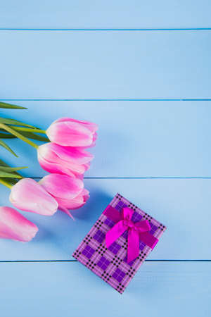 Bouquet of tender pink tulips with purple gift box on light blue wooden backgroundの写真素材