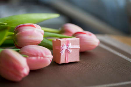 Bouquet of pink tulips with gift box on table.の写真素材