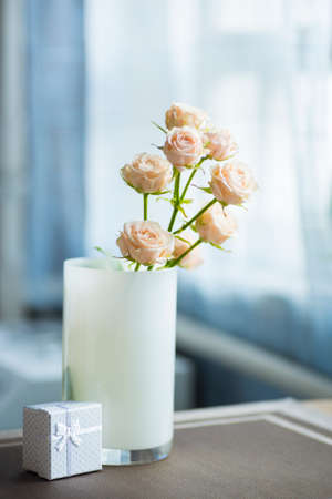 Bouquet of tender creamy roses in vase with white gift box.の写真素材