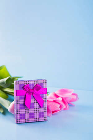 Bouquet of tender pink tulips with purple gift box on light blue wooden backgroundの写真素材