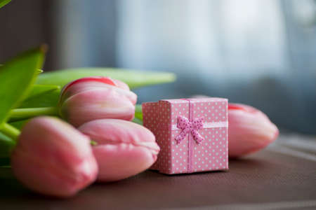 Bouquet of pink tulips with gift box on table.の写真素材