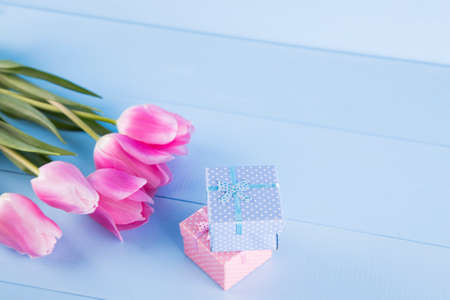 Bouquet of tender pink tulips with two gift boxes on light blue wooden backgroundの写真素材
