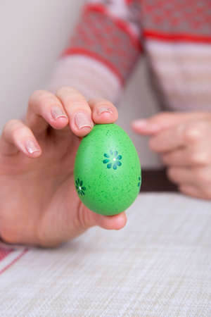Green colored easter egg in female hands.の写真素材
