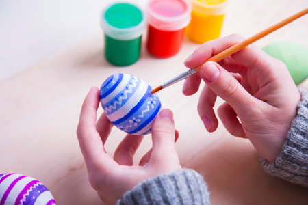 Female hands painting wooden easter egg with brush.の写真素材