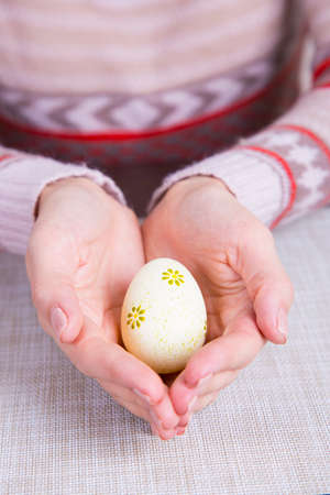 Yellow colored easter egg in female hands.の写真素材