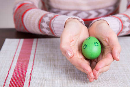 Green colored easter egg in female hands.の写真素材