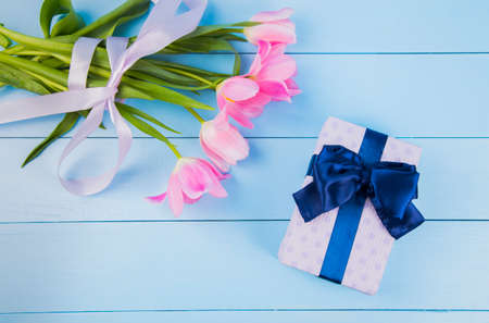 Bouquet of tender pink tulips with gift box on blue wooden background.の写真素材