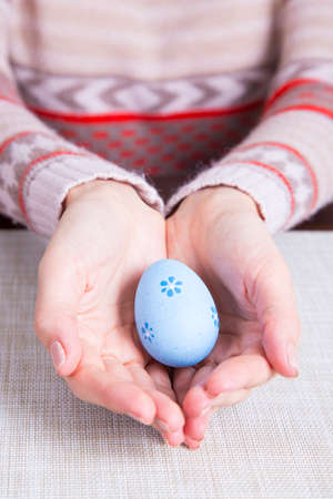 Blue colored easter egg in female hands.の写真素材