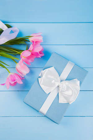 Bouquet of tender pink tulips with gift box on blue wooden background.の写真素材