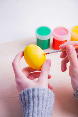 Female hands painting wooden easter egg with brush.の写真素材