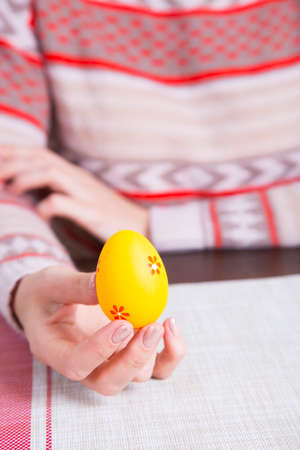 Orange colored easter egg in female hands.の写真素材