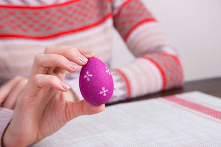 Crimson colored easter egg in female hands.の写真素材