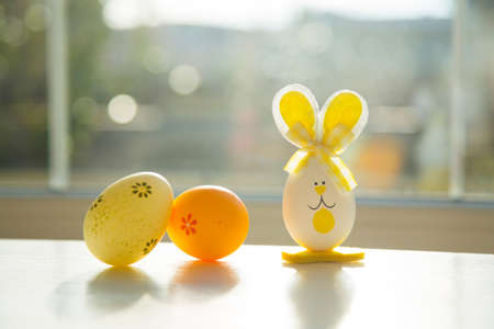 Funny toy rabbit with colorful easter eggs on window.の写真素材