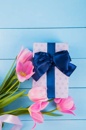 Bouquet of tender pink tulips with gift box on blue wooden background.の写真素材
