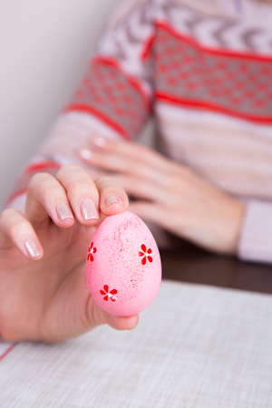 Pink colored easter egg in female hands.の写真素材