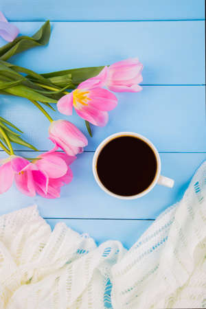 Bouquet of tender pink tulips with coffee cup and white fabric on blue wooden backgroundの写真素材