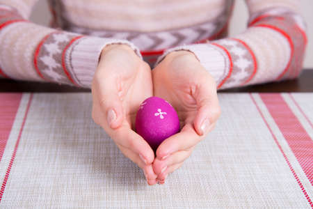 Crimson colored easter egg in female hands.の写真素材