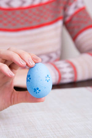 Blue colored easter egg in female hands.の写真素材
