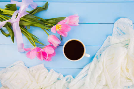 Bouquet of tender pink tulips with coffee cup and white fabric on blue wooden backgroundの写真素材