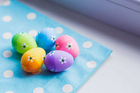 Colorful easter eggs on blue fabric near window.の写真素材