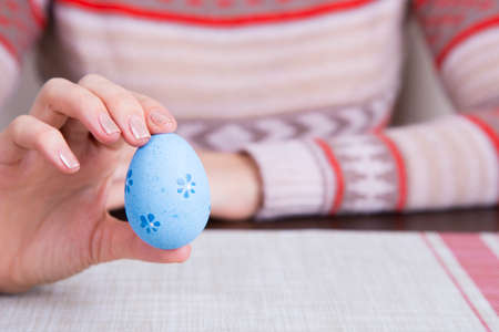 Blue colored easter egg in female hands.の写真素材