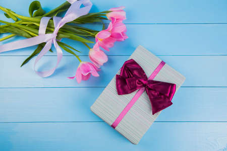 Bouquet of tender pink tulips with gift box on blue wooden background.の写真素材