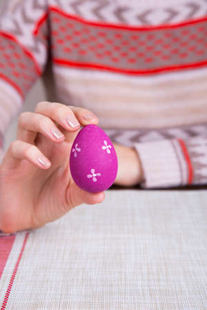 Crimson colored easter egg in female hands.の写真素材