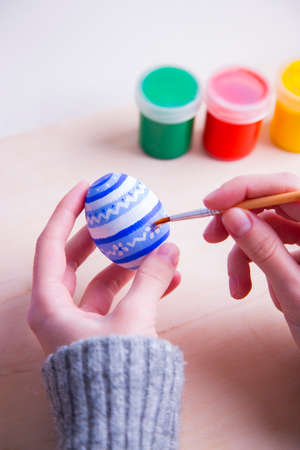 Female hands painting wooden easter egg with brush.の写真素材