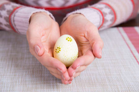 Yellow colored easter egg in female hands.の写真素材
