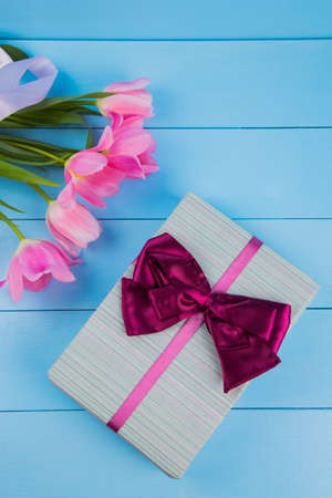 Bouquet of tender pink tulips with gift box on blue wooden background.の写真素材