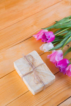 Bouquet of tender pink and white tulips with beautiful colored gift box on light wooden background.の写真素材