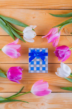 Beautiful bouquet of tender pink and white tulips with colorful gift box on light wooden backgroundの写真素材