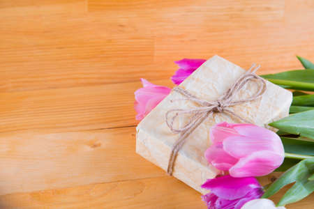 Bouquet of tender pink and white tulips with beautiful colored gift box on light wooden background.の写真素材