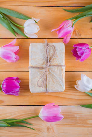 Beautiful bouquet of tender pink and white tulips with colorful gift box on light wooden backgroundの写真素材