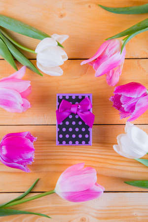 Beautiful bouquet of tender pink and white tulips with colorful gift box on light wooden backgroundの写真素材