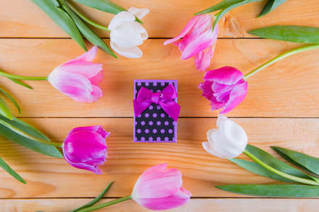 Beautiful bouquet of tender pink and white tulips with colorful gift box on light wooden backgroundの写真素材