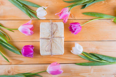 Beautiful bouquet of tender pink and white tulips with colorful gift box on light wooden backgroundの写真素材