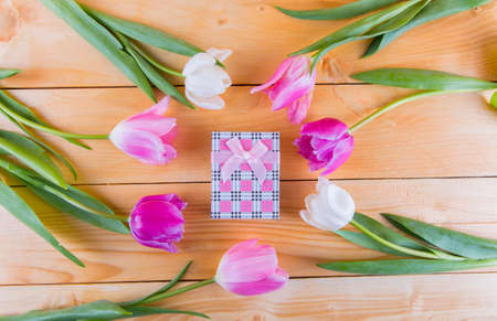 Beautiful bouquet of tender pink and white tulips with colorful gift box on light wooden backgroundの写真素材