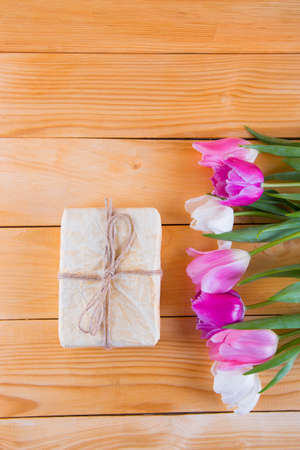 Bouquet of tender pink and white tulips with beautiful colored gift box on light wooden background.の写真素材