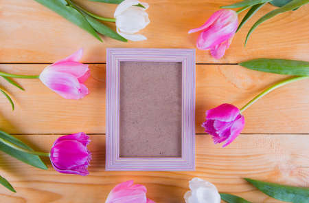 Bouquet of tender pink tulips with empty photo frame on light wooden background.の写真素材
