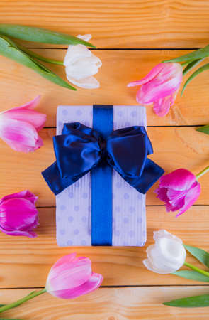 Beautiful bouquet of tender pink and white tulips with colorful gift box on light wooden backgroundの写真素材