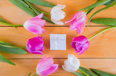 Beautiful bouquet of tender pink and white tulips with colorful gift box on light wooden backgroundの写真素材