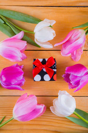 Beautiful bouquet of tender pink and white tulips with colorful gift box on light wooden backgroundの写真素材