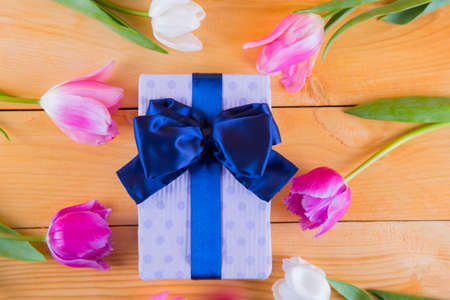 Beautiful bouquet of tender pink and white tulips with colorful gift box on light wooden backgroundの写真素材
