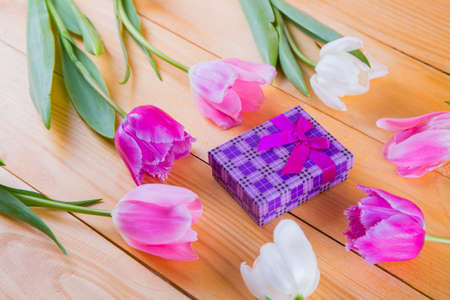 Beautiful bouquet of tender pink and white tulips with colorful gift box on light wooden backgroundの写真素材