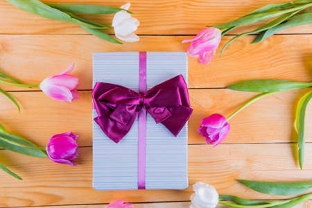 Beautiful bouquet of tender pink and white tulips with colorful gift box on light wooden backgroundの写真素材